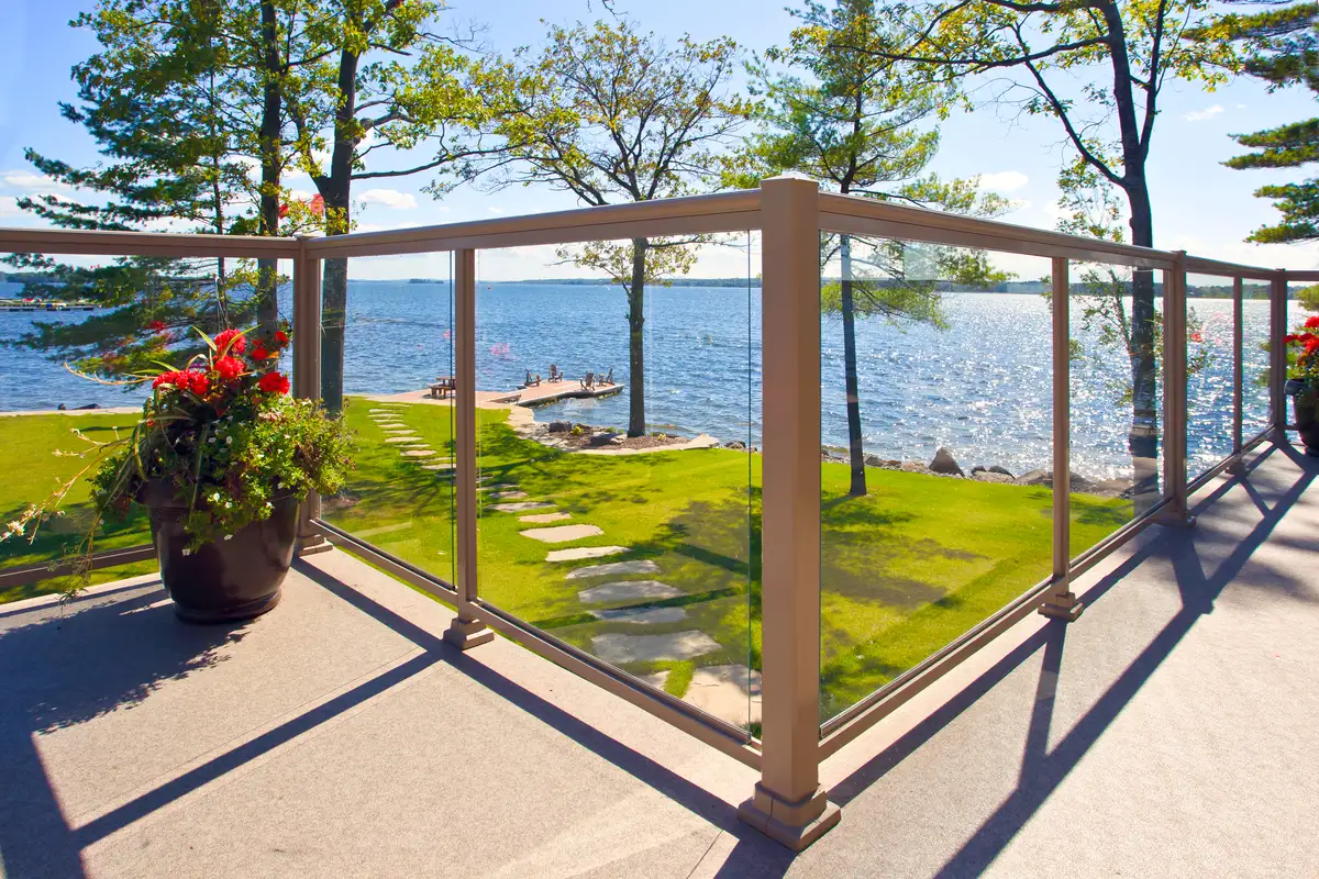 Modern glass and aluminum railing system on a waterfront deck overlooking a lake and private dock.