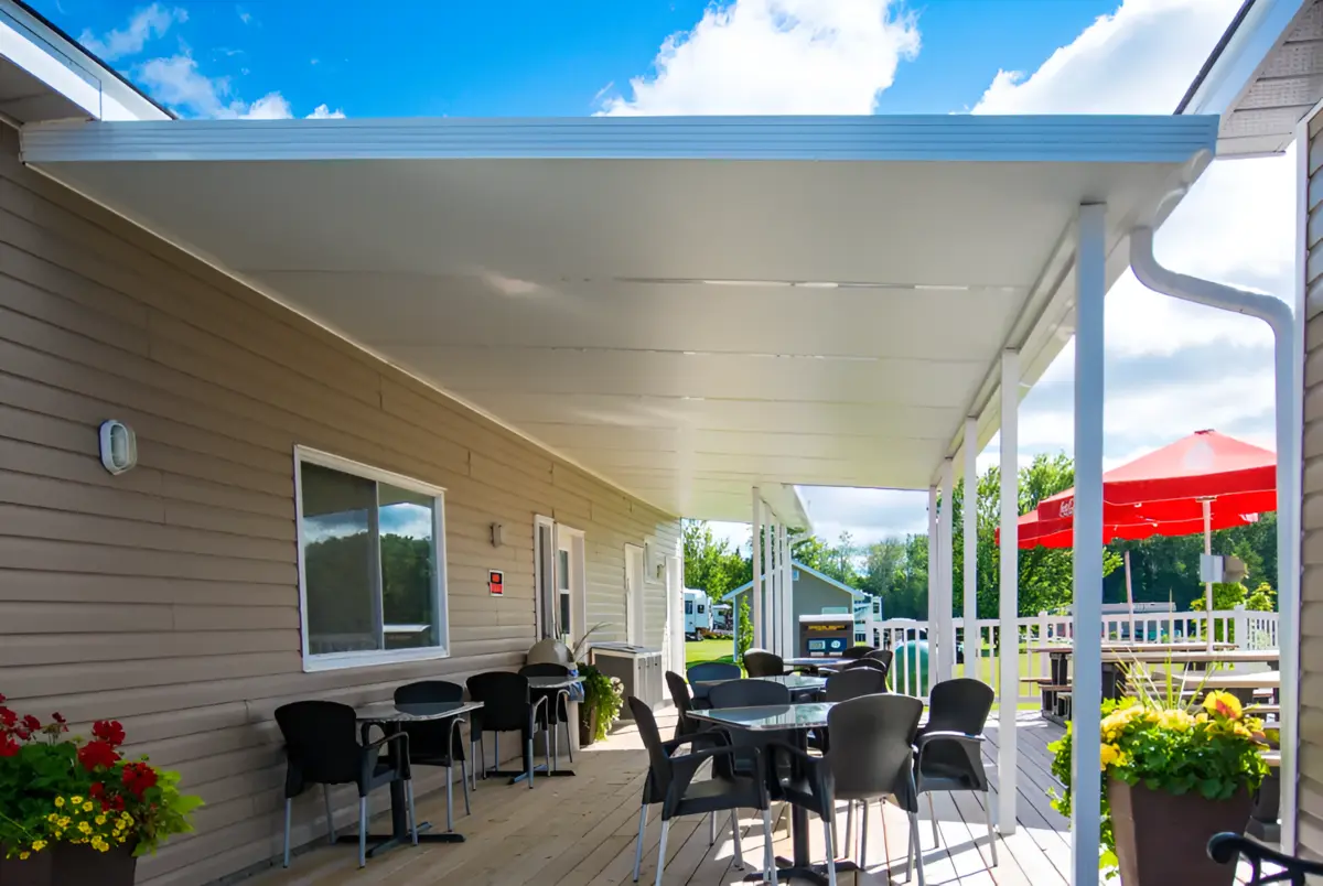 A large, dark-framed solid insulated patio cover providing total shade over a modern lounge area on a grey deck.